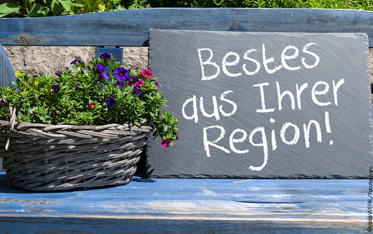 Tafel mit Aufschrift "Bestes aus Ihrer Region" neben Blumenkübel