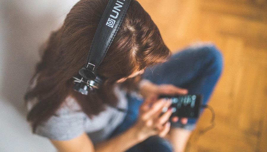 Frau hört Podcast mit Kopfhörern über Smartphone