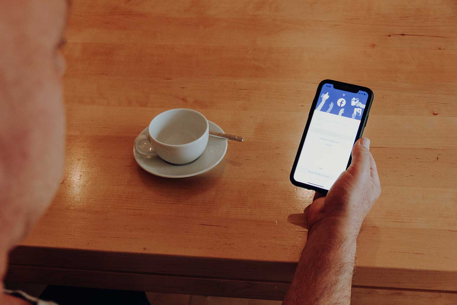 Mann hält Handy mit geöffneter Facebook-App