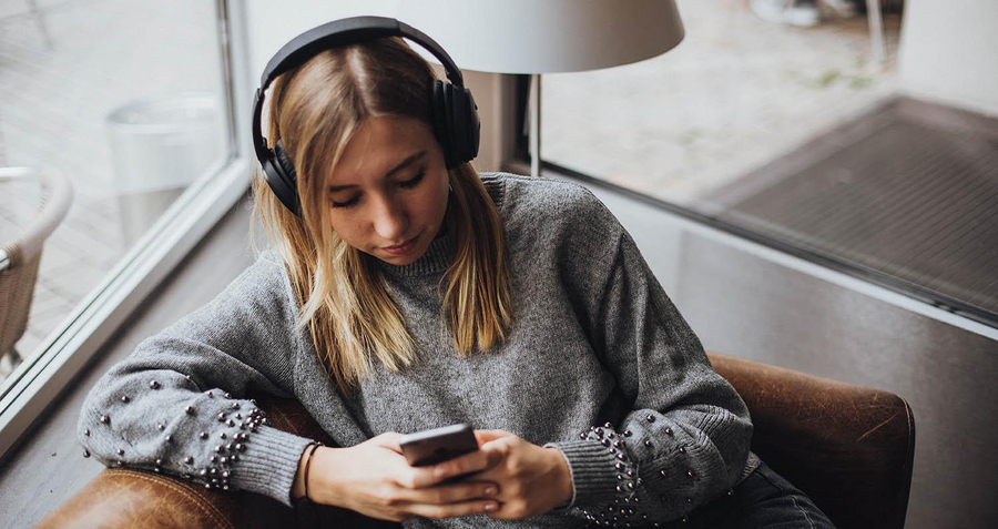 junge Frau hört Podcast per Kopfhörer