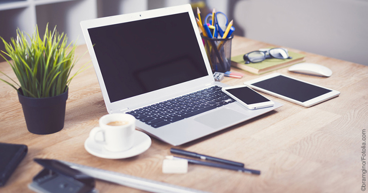 Schreibtisch mit Laptop, Smartphone, Tablet, Kaffeetasse und Büroutensilien