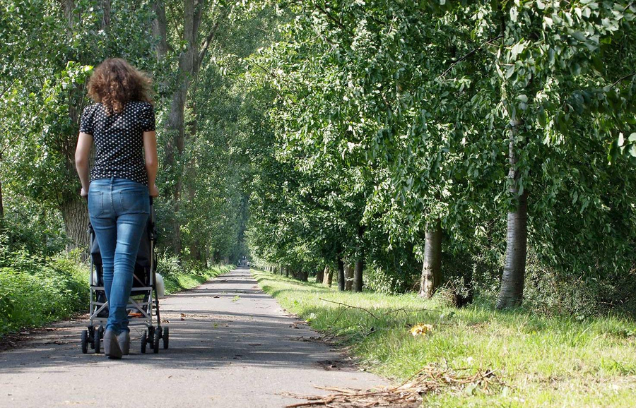 Frau geht mit Kinderwagen spazieren