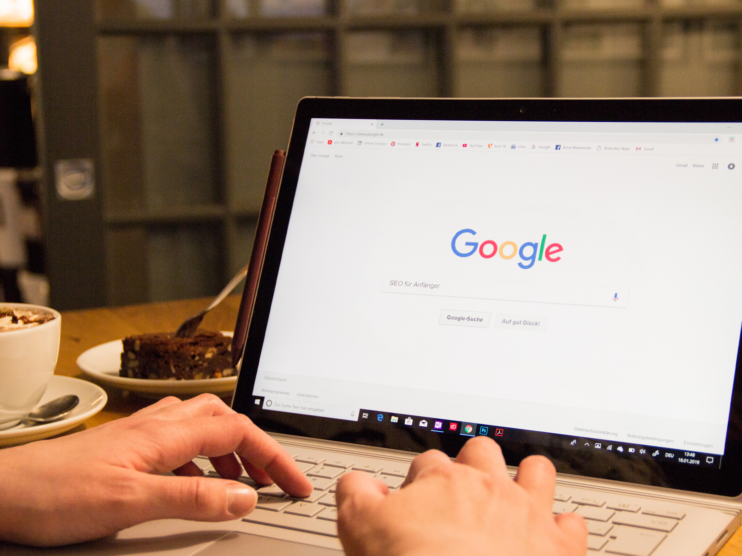 Google auf Laptop geöffnet, Hände tippen auf der Tastatur